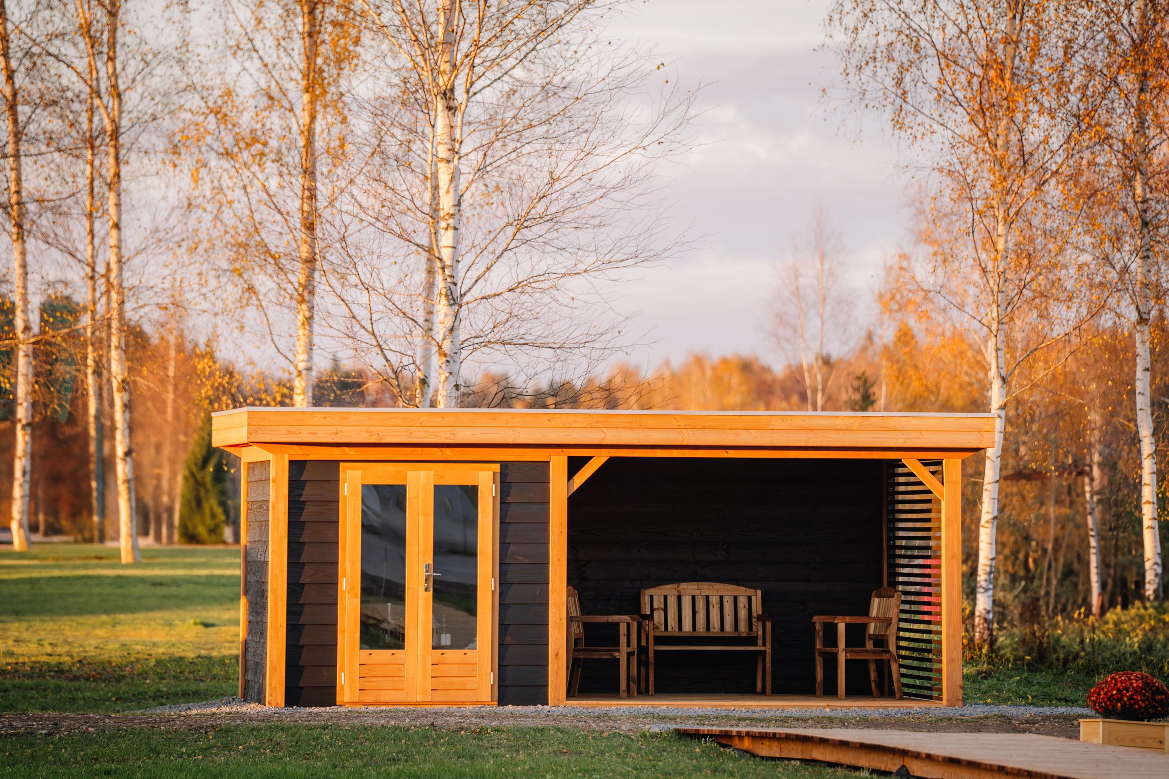 Houten tuinkamer met open overkapping in de avondzon