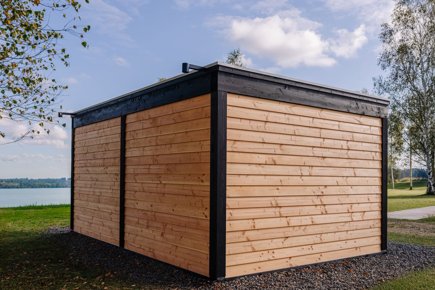 Houten tuinhuis met horizontale delen en zwarte kanten aan het water